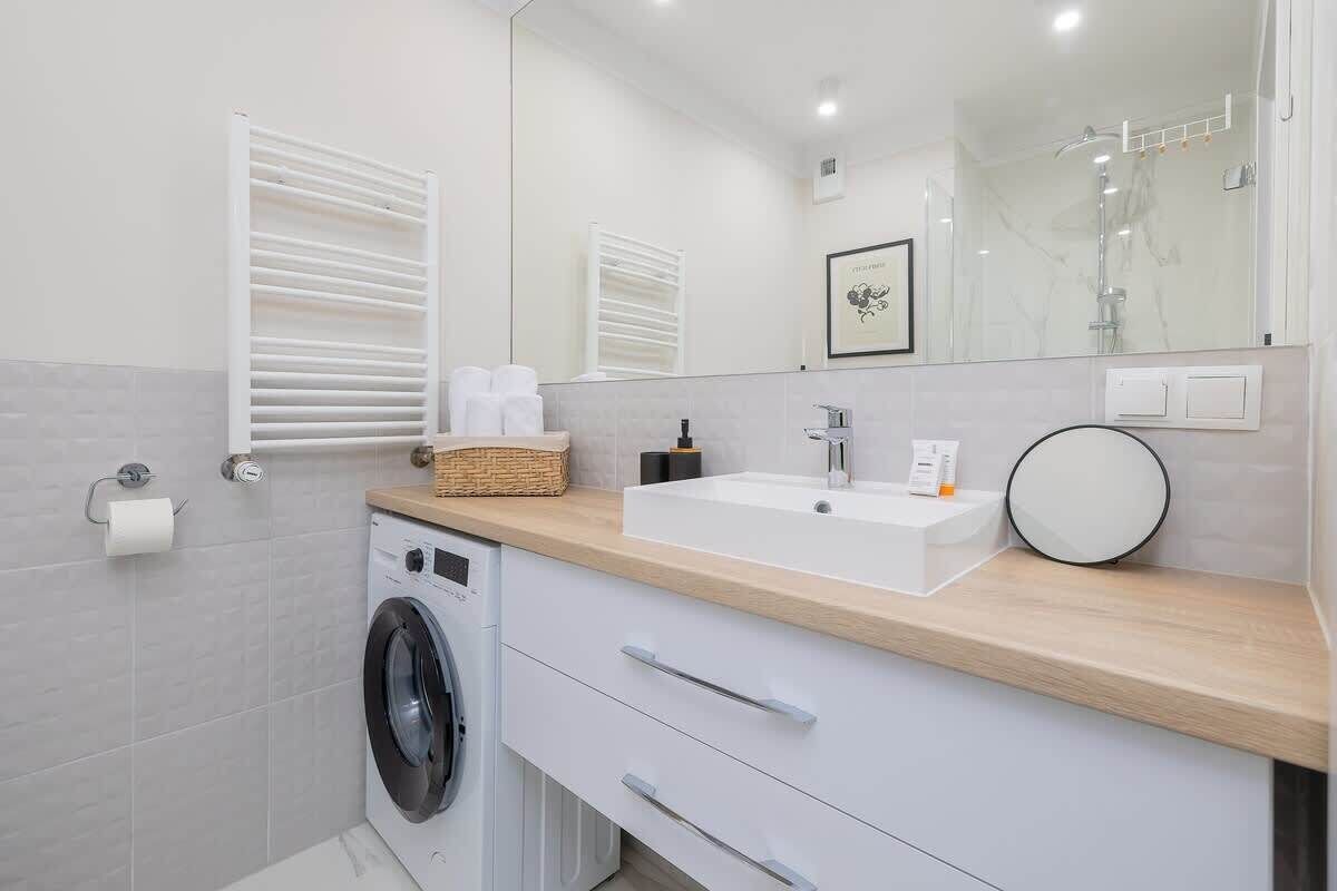 Een moderne badkamer met een wasmachine, een wastafel en een spiegel.