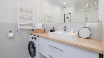 Een moderne badkamer met een wasmachine, een wastafel en een spiegel.