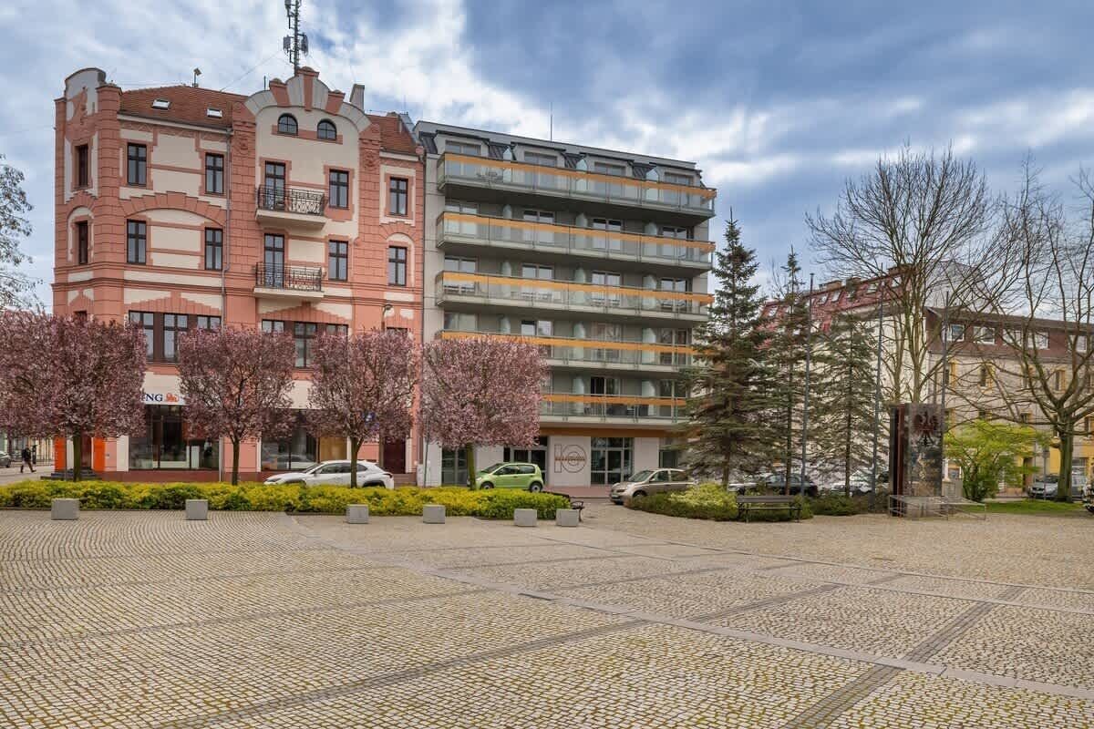En byggnad med flera våningar som kombinerar olika arkitektoniska stilar, inklusive en rosa fasad med balkonger och en modern grå byggnad med balkonger.