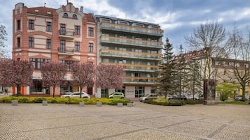En byggnad med flera våningar som kombinerar olika arkitektoniska stilar, inklusive en rosa fasad med balkonger och en modern grå byggnad med balkonger.