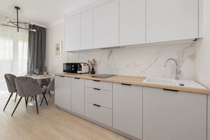 Una cocina moderna con armarios blancos, encimera de mármol y lavabo integrado.