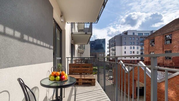 A balcony with a table, chairs, and a wooden bench. - Comfortable Apartment | Balcony, Workspace, High Speed WiFi (Łódź)