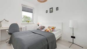 A bedroom with a bed, desk, chair, lamp, and window. - Comfortable Apartment | Balcony, Workspace, High Speed WiFi (Łódź)