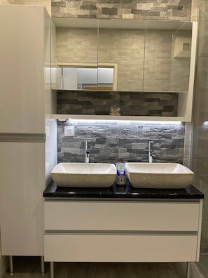 A modern kitchen with two sinks, a stone backsplash, and white cabinetry. - Beautiful 2-bed Apartment in Wien (Vienna)