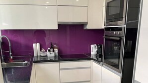 A modern kitchen with white cabinets, a purple backsplash, and a stainless steel oven. - Beautiful 2-bed Apartment in Wien (Vienna)