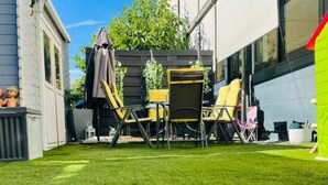 A well-maintained lawn with a patio area featuring outdoor furniture, including chairs and a table. - Beautiful 2-bed Apartment in Wien (Vienna)