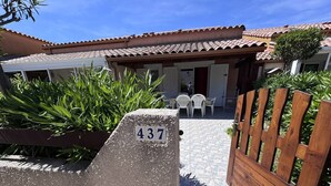 Une villa dotée d’un patio carrelé, d’un portail en bois et d’une plaque indiquant le numéro de la maison.