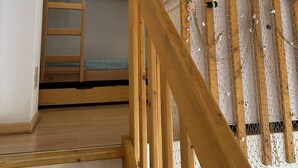 Un escalier en bois, avec un lit superposé en haut.