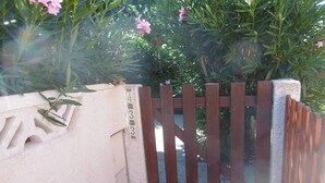 Une entrée fermée par un portail, agrémentée d’une clôture en bois, d’un mur en béton et d’un petit élément décoratif.