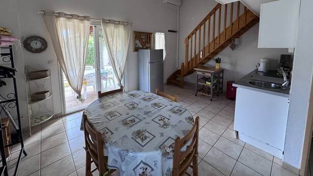 Une cuisine compacte comprenant un coin repas, un escalier et une petite table avec un réfrigérateur.
