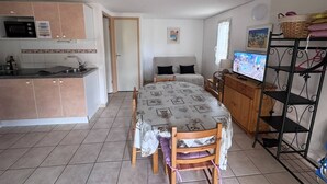 Une chambre compacte comprenant un coin cuisine, un lit avec télévision et un espace repas.