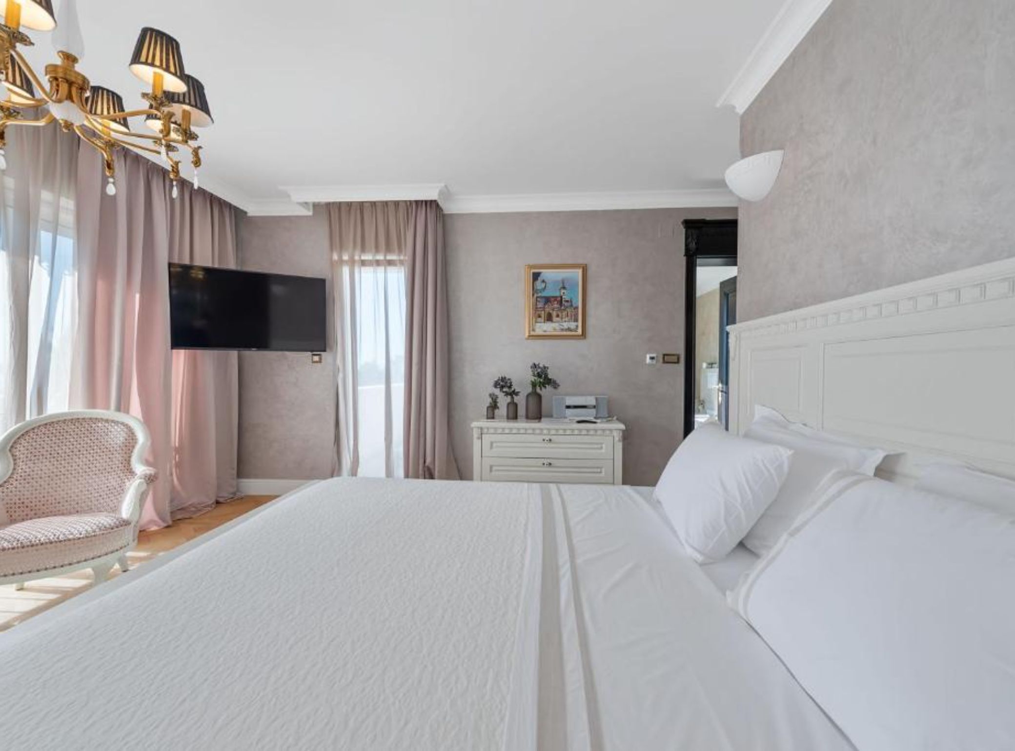 Habitación de hotel con una cama grande, un aparador, una televisión y una silla.