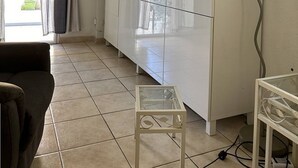 A living room with a sofa, a TV on a stand, a cabinet, and a small table.