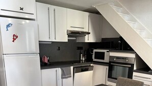 A compact kitchen with white cabinets, a built-in oven, a microwave, and a dining area with a table and chairs.