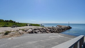 A paved walkway leading to a rocky shoreline with a picnic table and a bench. - Private Lake Access, Great for Families! (Orleans)
