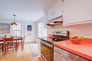 A modern kitchen with white cabinets, a stainless steel oven, and a red countertop.