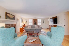 A living room with a fireplace, a sofa, armchairs, a coffee table, and a television. - Private Lake Access, Great for Families! (Orleans)