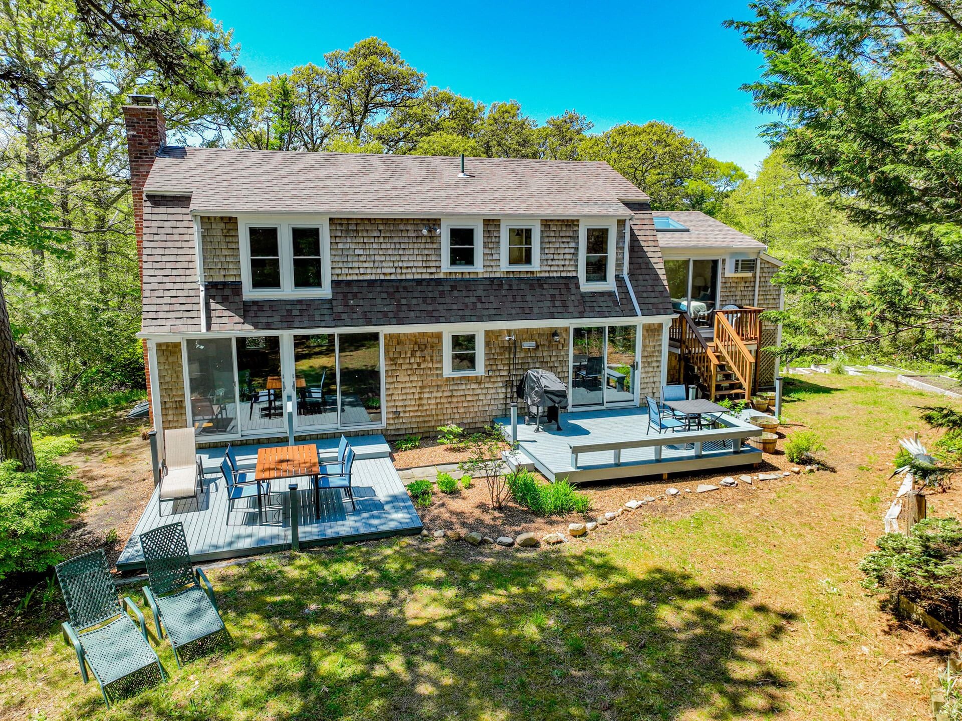 A two-story house with a covered patio, outdoor seating, and a deck.