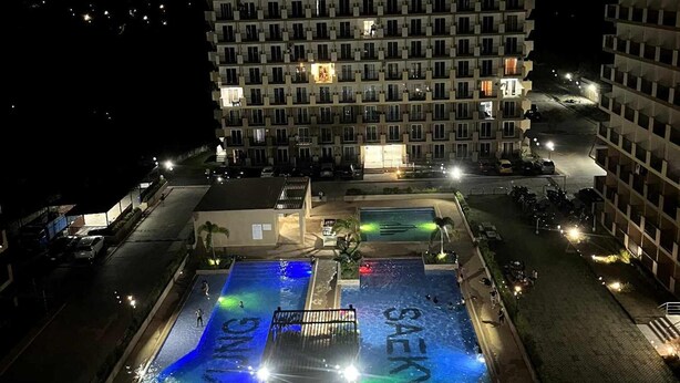 Ein Poolbereich auf dem Dach mit mehreren Pools und einem großen Gebäude im Hintergrund.