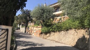 Un étroit sentier pavé mène à un bâtiment aux murs de pierre, doté d’un balcon.