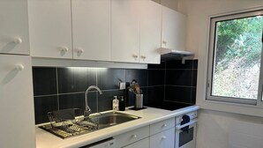 Une cuisine moderne avec des meubles blancs, un évier en acier inoxydable et un lave-vaisselle.