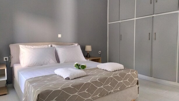 A bedroom with a bed, nightstands, a wardrobe, and a small plant on the bed. - Samos Home by the sea (Samos)