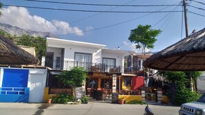 A two-story building with a balcony, a restaurant named "Evis Beer Bar" on the ground floor, and a blue garage door to the left. - Samos Home by the sea (Samos)