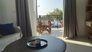 A room with a view of a balcony, a table with a tray, and a sofa with a blue pillow. - Samos Home by the sea (Samos)