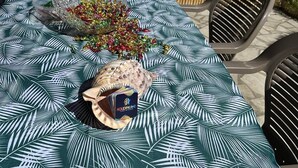 A round table with a palm leaf pattern tablecloth, a decorative bowl, and a small gift box.