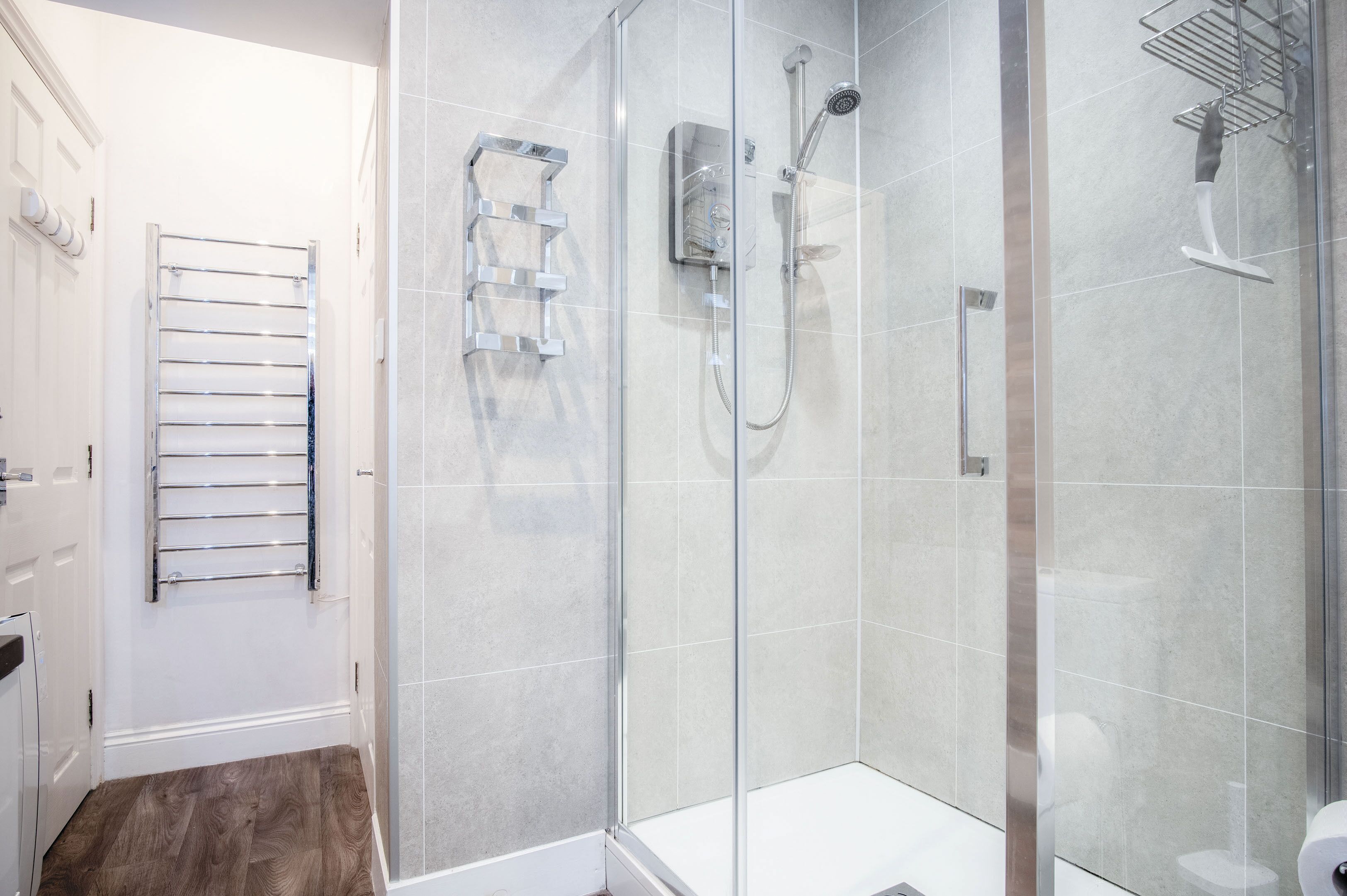 Une salle de bain moderne dotée d’une douche à parois de verre, d’un porte-serviettes et de toilettes.