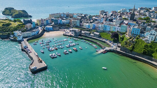 A coastal town with a marina, historic buildings, and a prominent church spire.