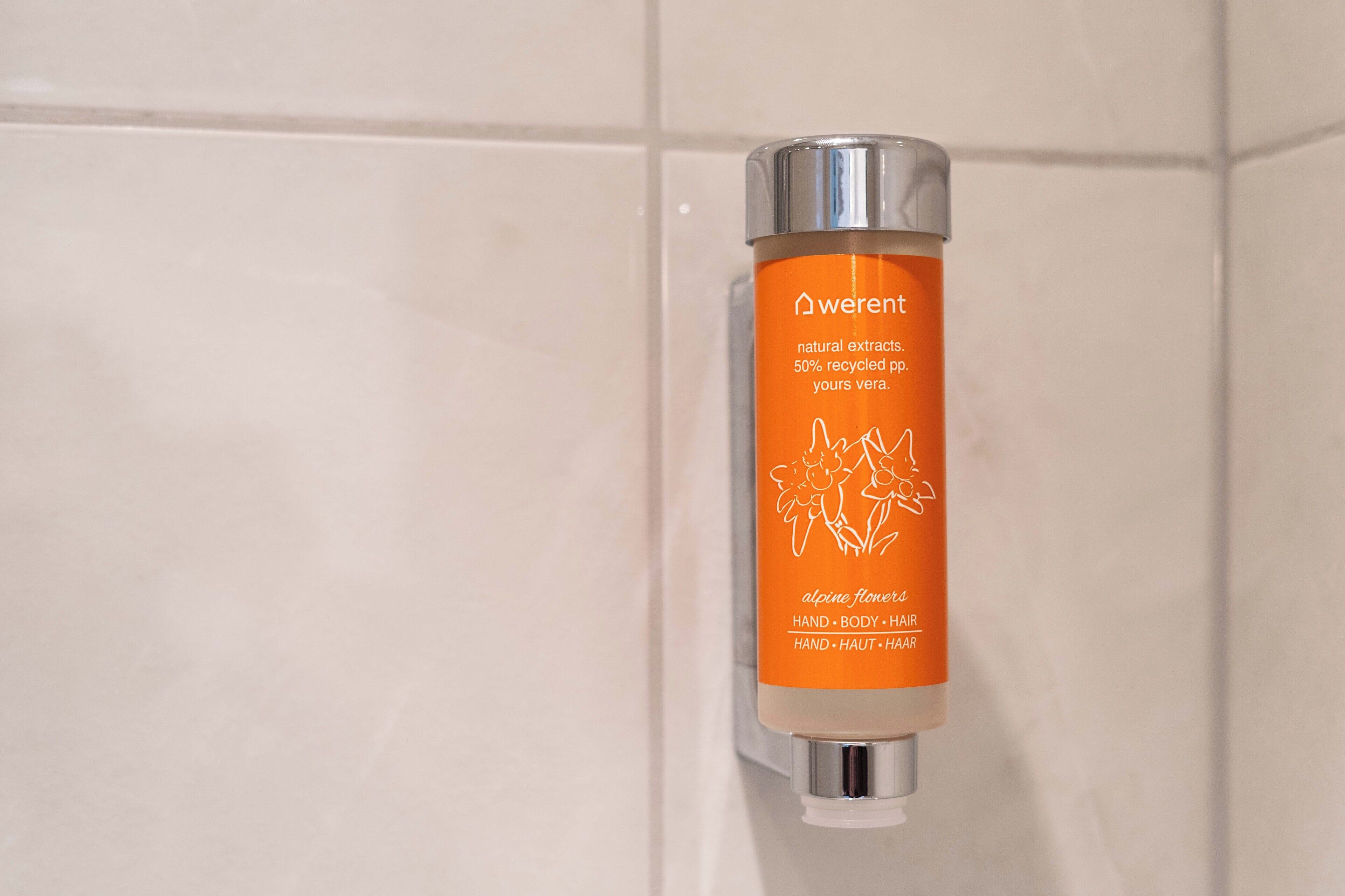 A bottle of Werent natural extracts, 50% recycled paper, and alpine flowers hand, body, hair shampoo.