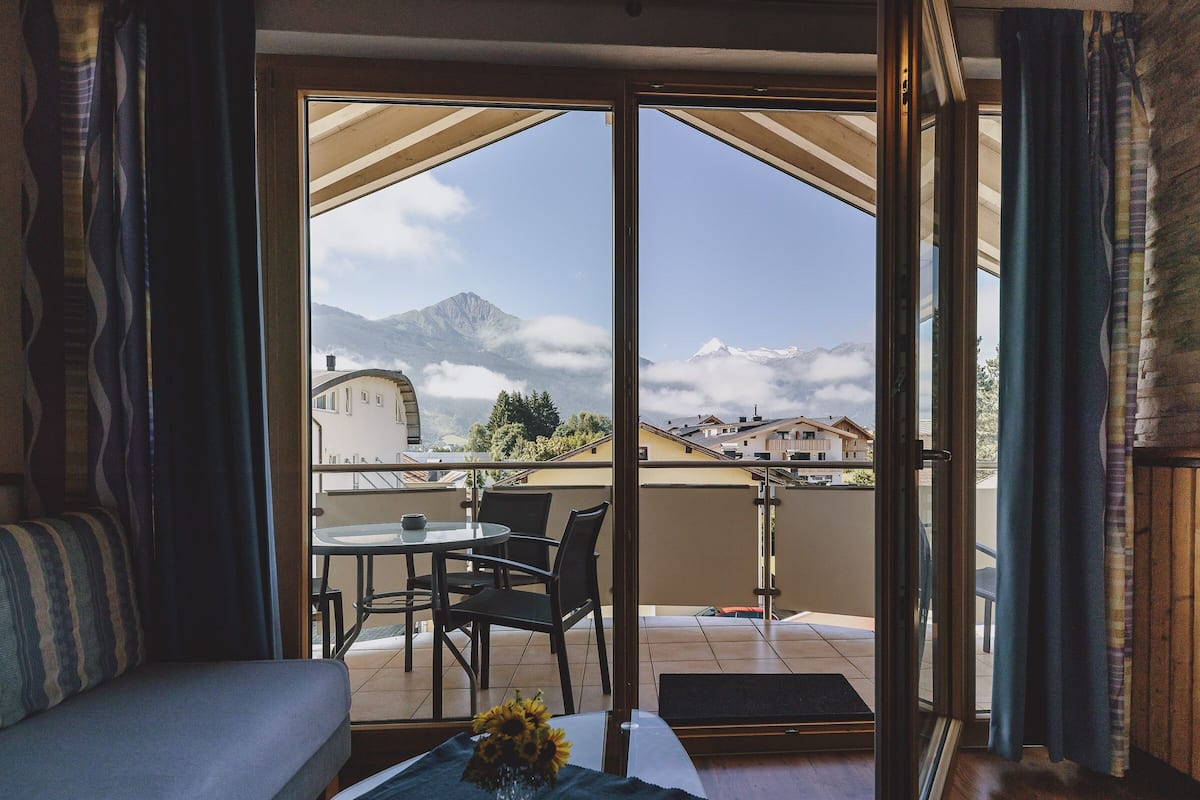 A balcony with a table, chairs, and a sofa.