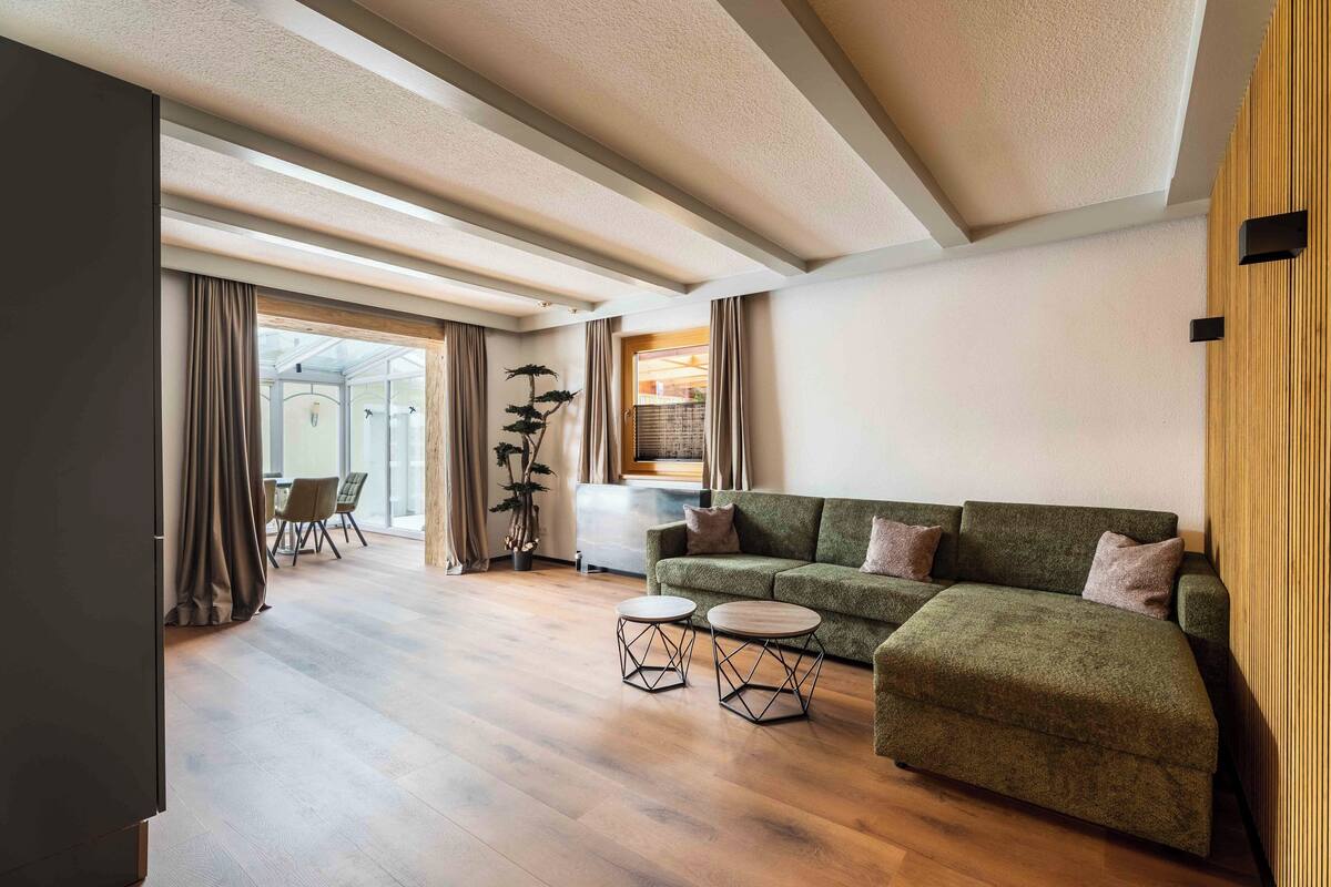 A modern living room with a green sofa, two round coffee tables, and a wooden floor.
