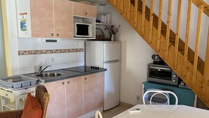 Eine kompakte Küche mit Mikrowelle, Kühlschrank und einer kleinen Essecke mit Tisch und Stühlen.