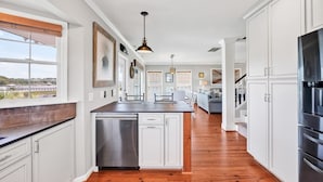 A modern kitchen with white cabinetry, stainless steel appliances, and a wooden countertop. - Spacious 5BR, 4BA home at Holden Beach with stunning water views. (Holden Beach)