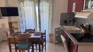 Une cuisine compacte comprenant une table à manger, des chaises, un téléviseur et un four à micro-ondes.
