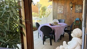 Une terrasse en bois avec une table et des chaises, une sculpture décorative et une vue sur l’extérieur.