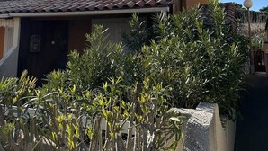 Un immeuble résidentiel avec un toit recouvert de tuiles, une antenne parabolique et une végétation luxuriante au premier plan.