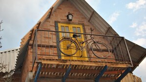 Un edificio de ladrillo con una puerta amarilla y una bicicleta sobre la barandilla de un balcón.