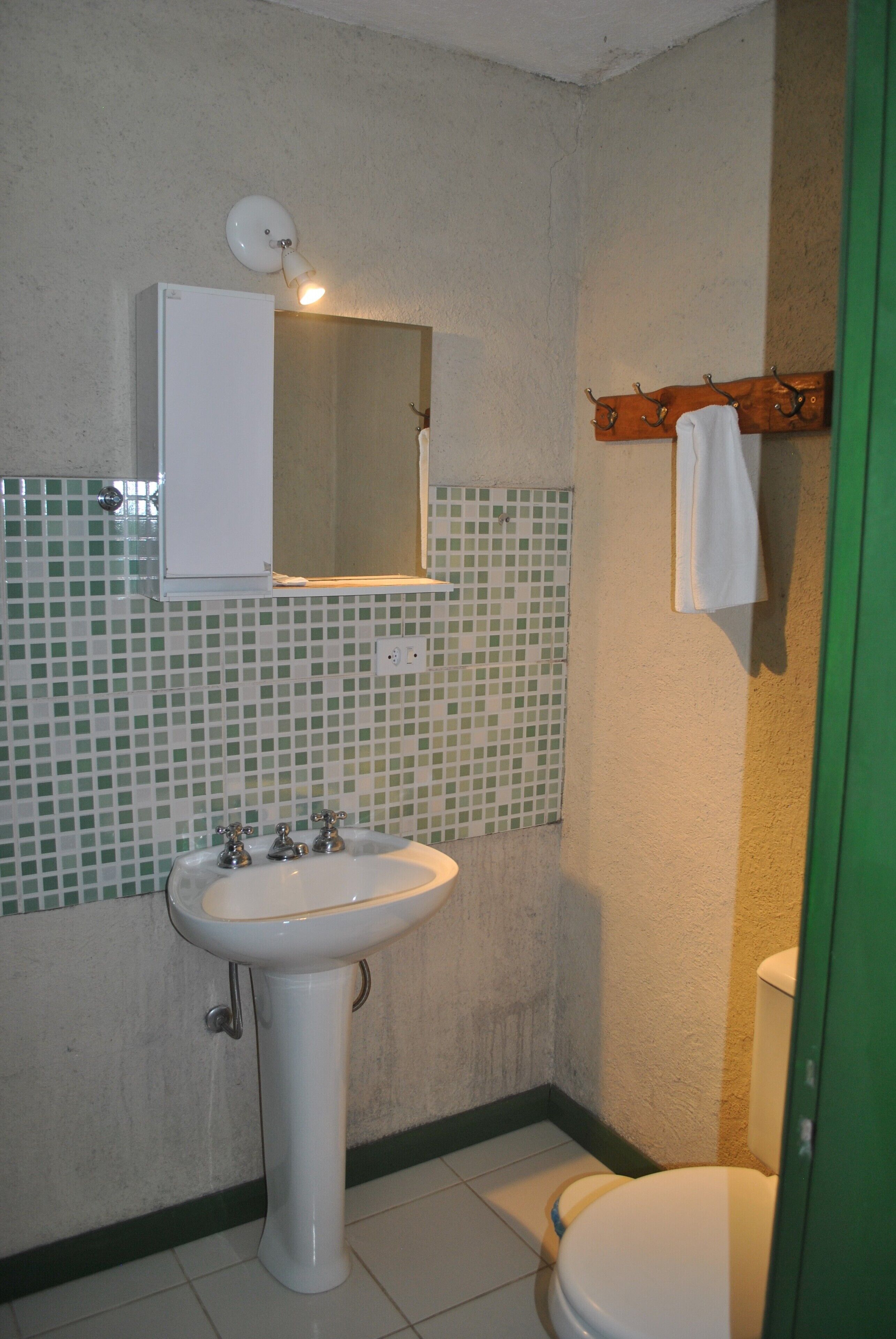 Une salle de bain avec un lavabo blanc, un miroir et des toilettes.