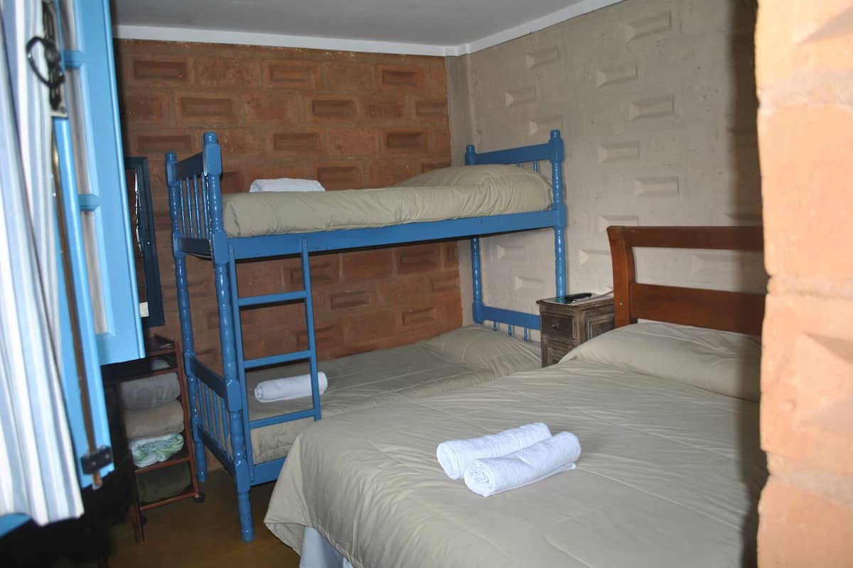 Dormitorio con literas, pared de ladrillo y cabecero de madera.