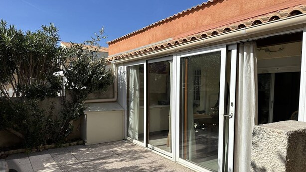 Ein Patio mit Fliesenboden, einer Schiebetür und einem gefliesten Dach.