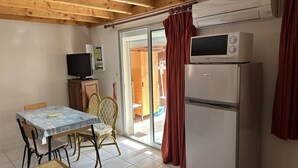 Eine kleine Küche mit Essbereich, einem Fernseher und einem Kühlschrank.