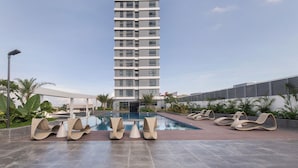 Ein modernes Hotel mit Poolbereich, Liegestühlen und freiem Blick auf das Gebäude.