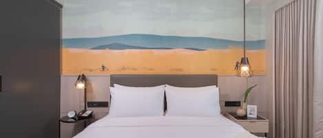 Quarto de hotel moderno com uma cama grande, duas mesas de cabeceira, um criado-mudo, uma luminária de parede e uma pintura de paisagem desértica.