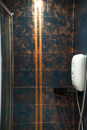 Een badkamer met donkerblauwe tegels en een enkele oranje streep.