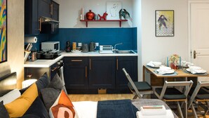 A compact living space with a kitchenette, a dining area, and a bed with multiple pillows.