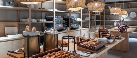 Un bufé de desayuno con lámparas colgantes de mimbre, estantes de madera y una máquina de café.