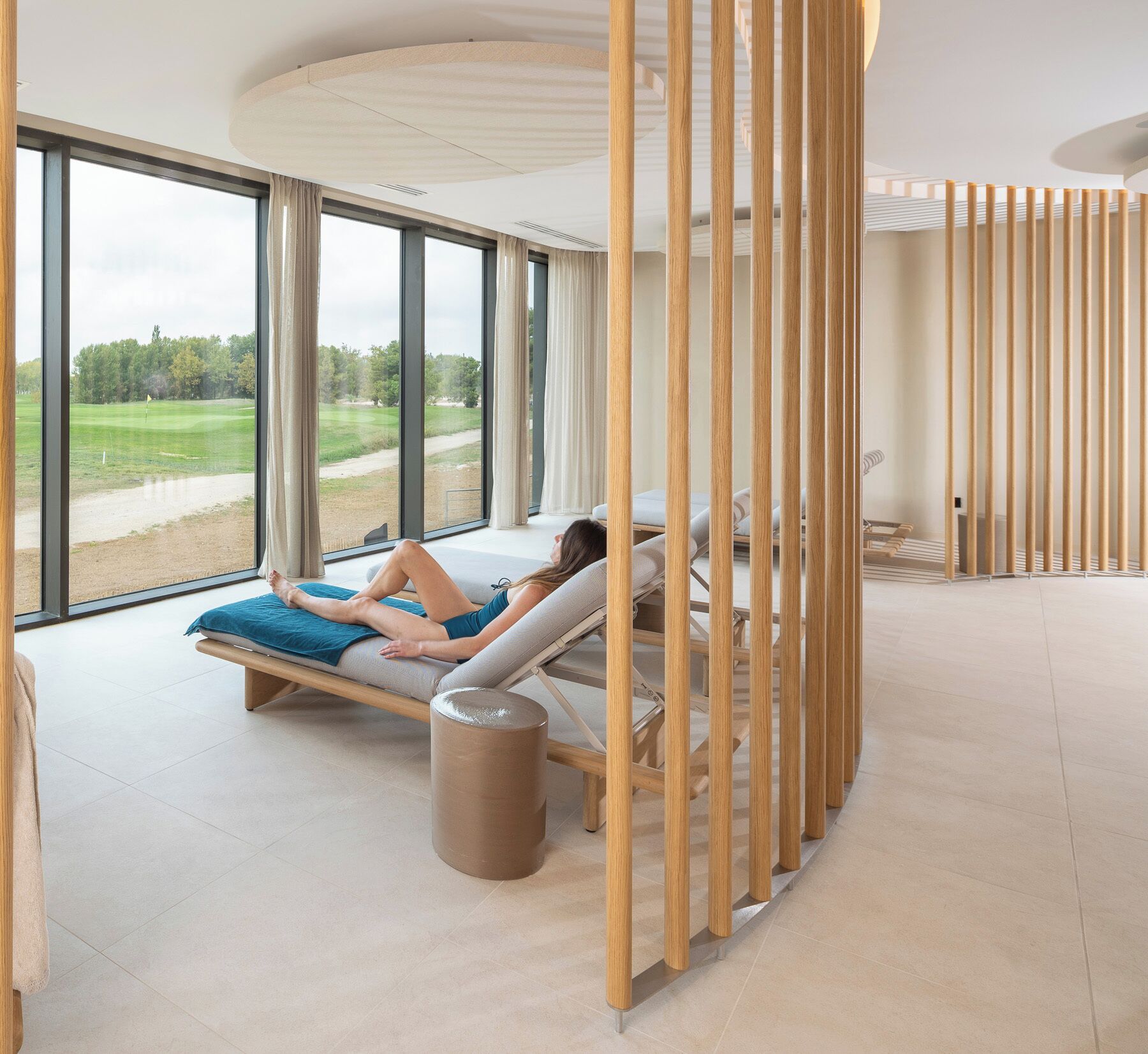 Une salle de spa dotée de grandes fenêtres, d’une table de massage et d’une cloison en bois.